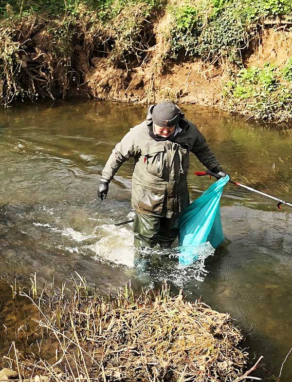 Man in river collecting rubbish